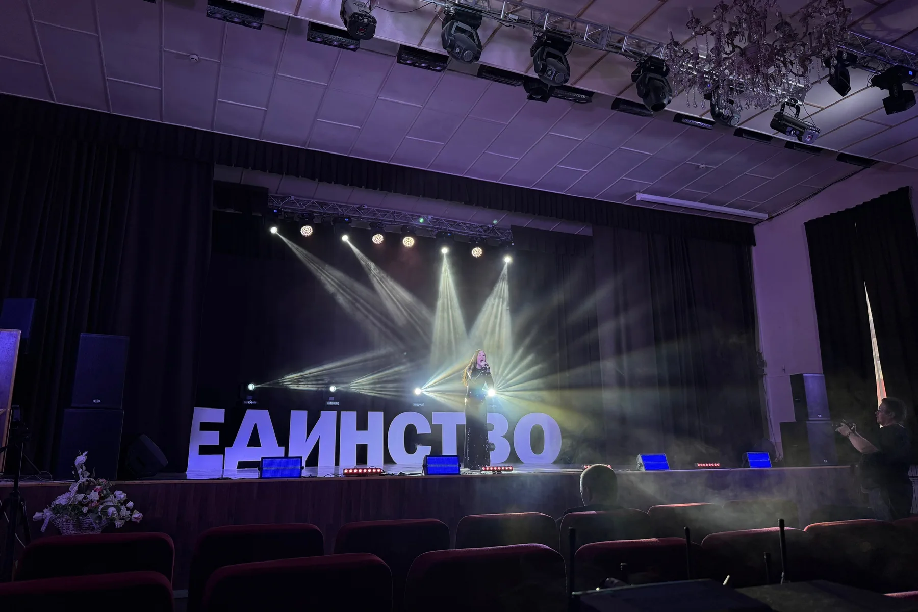 Артист на сцене в веере белых световых лучей